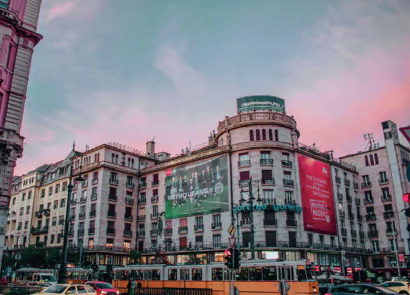 A city street corner with a mix of old and modern-style buildings and a large billboard.
