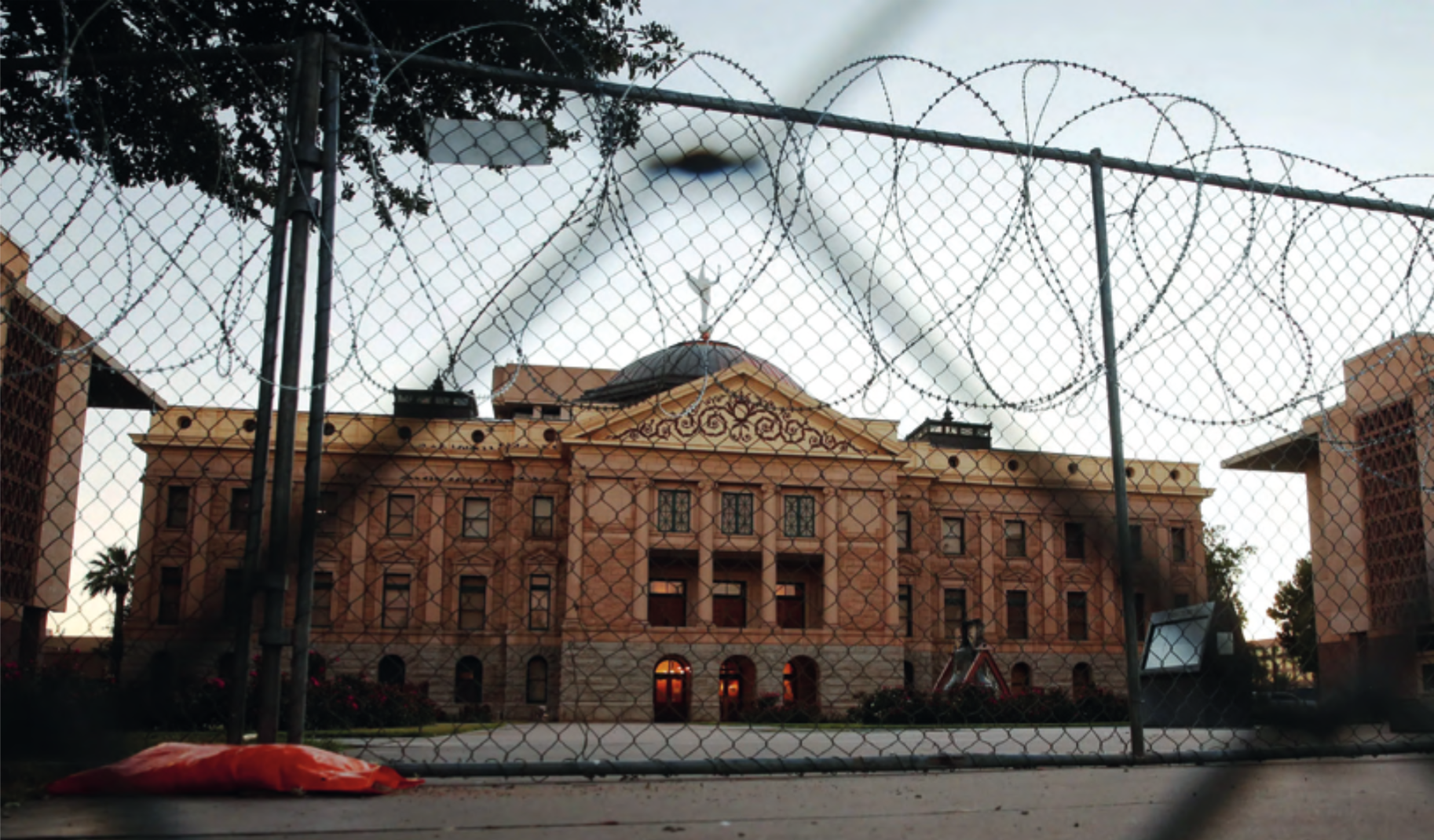 A grand municipal building behind a barbed wire fence