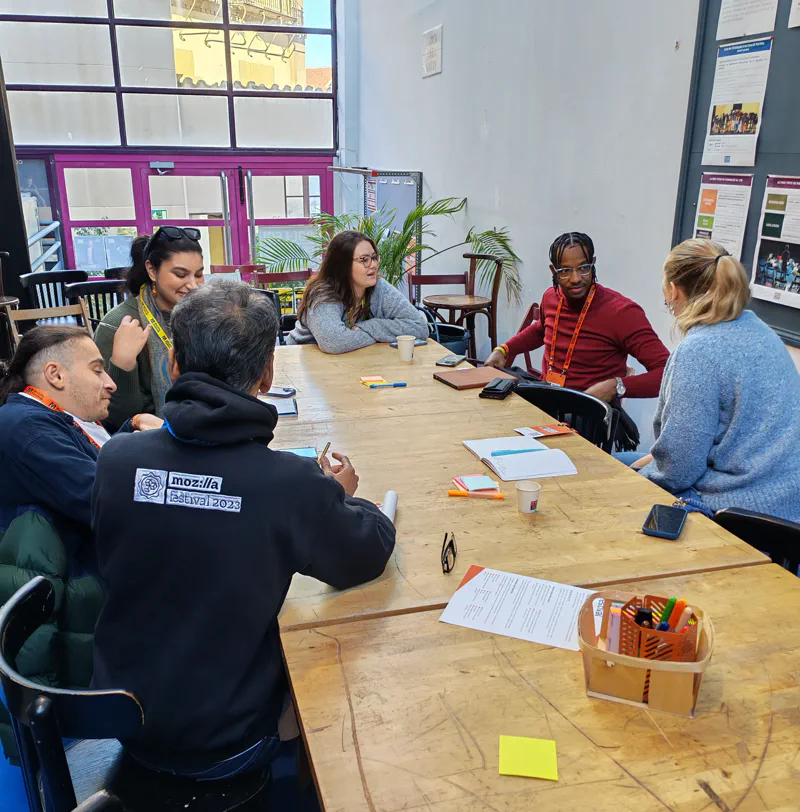 A group of participants sitting at a table engaged in a discussion.