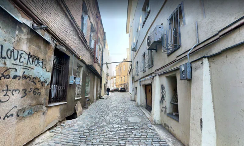 A narrow cobblestone street with buildings on either side.